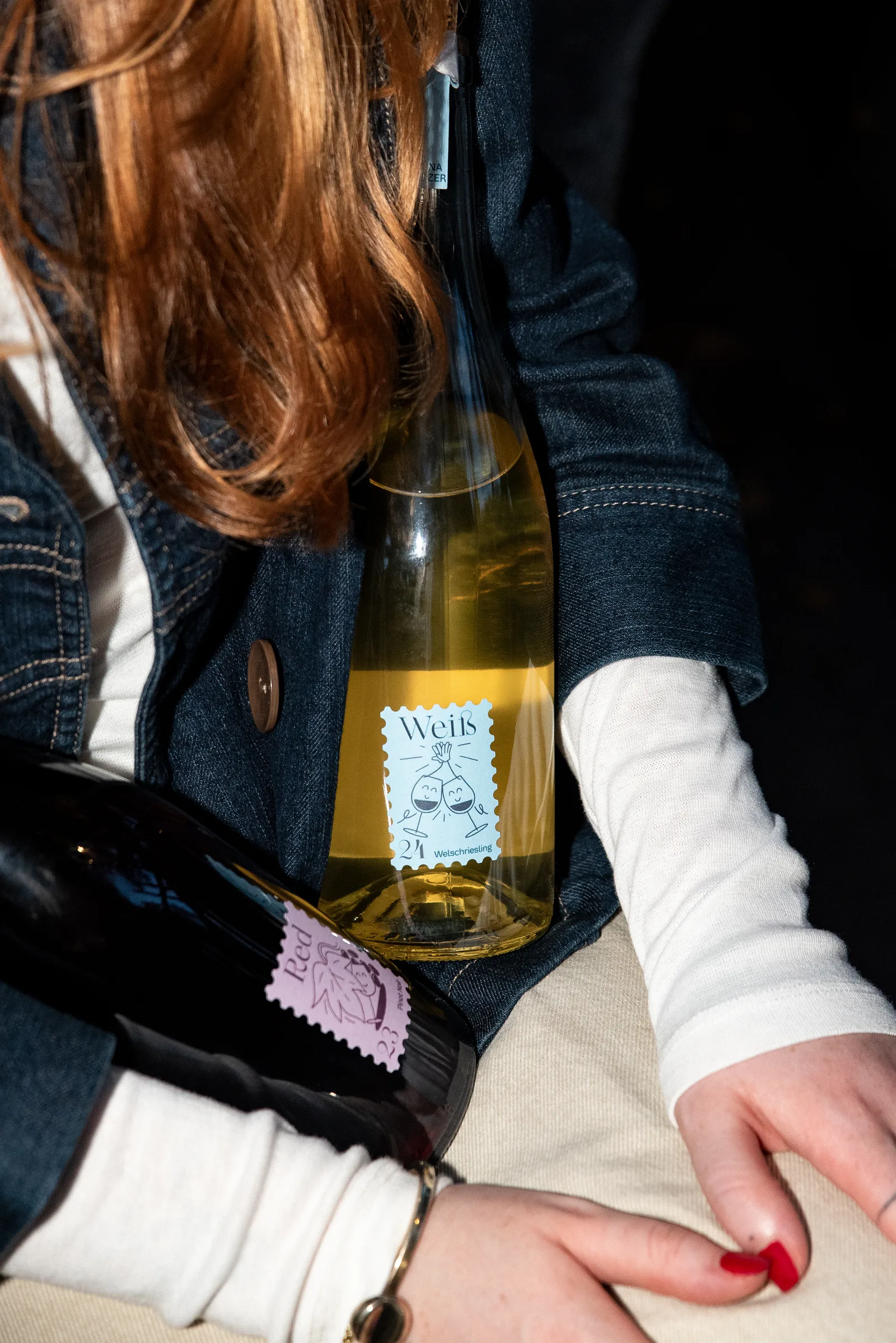Two wine bottles tucked beneath a woman's denim jacket