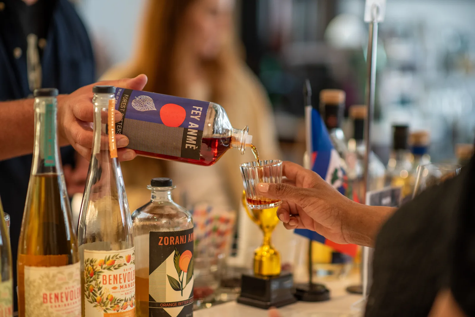 Liqueur being poured into a small glass at a tasting booth