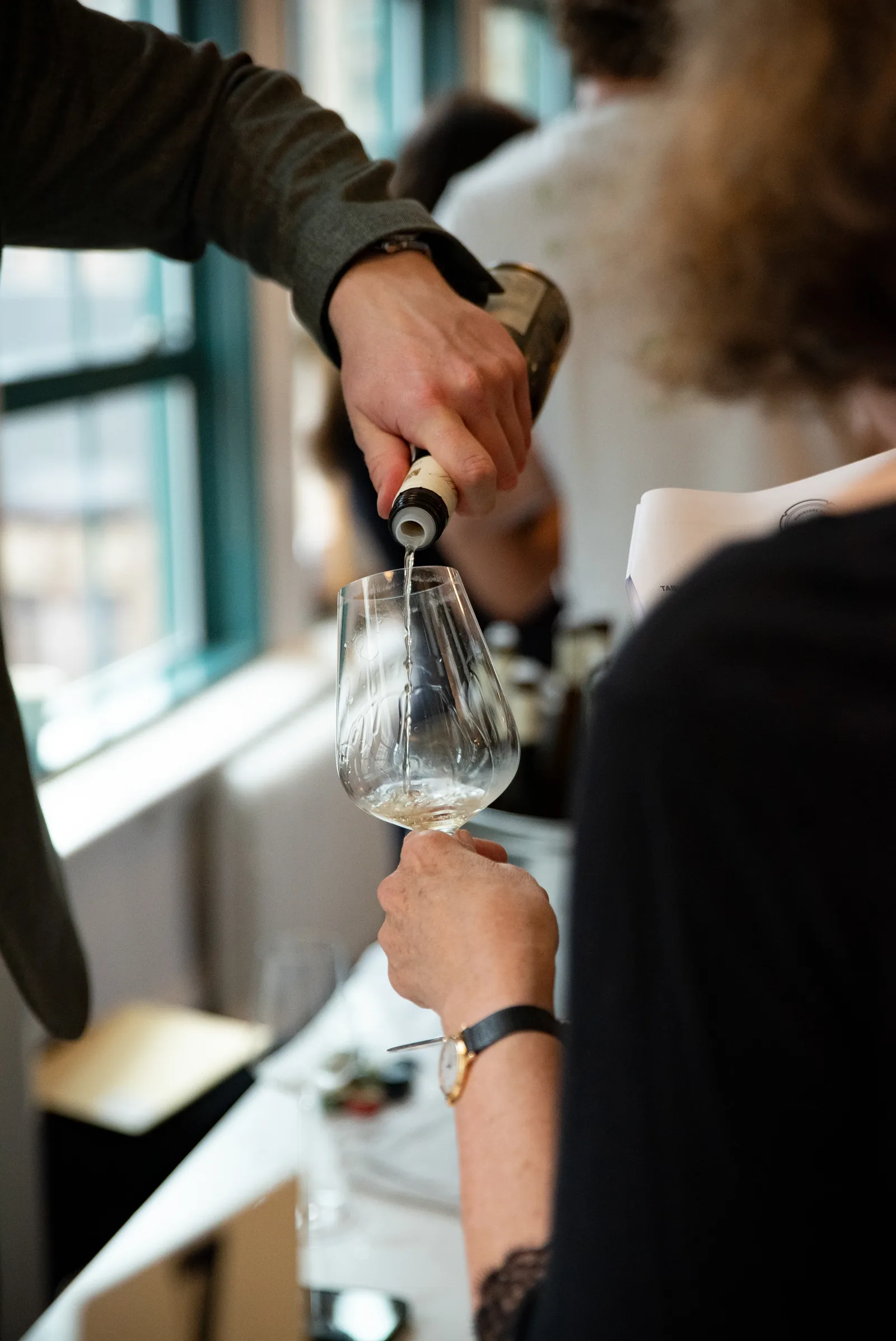 Wine being poured into a glass at a tasting